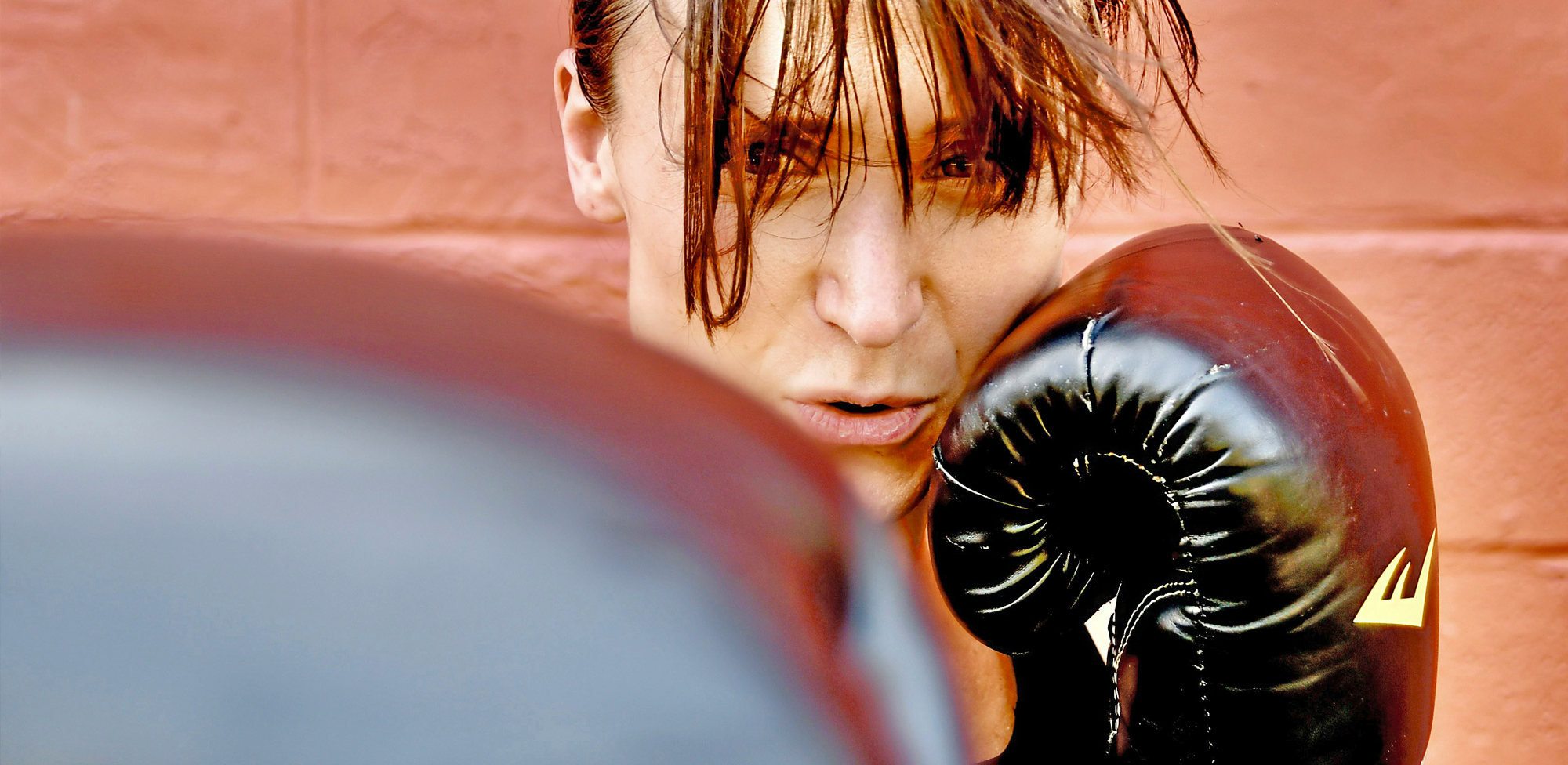 Close up on woman wearing black boxing gloves throwing punches during training