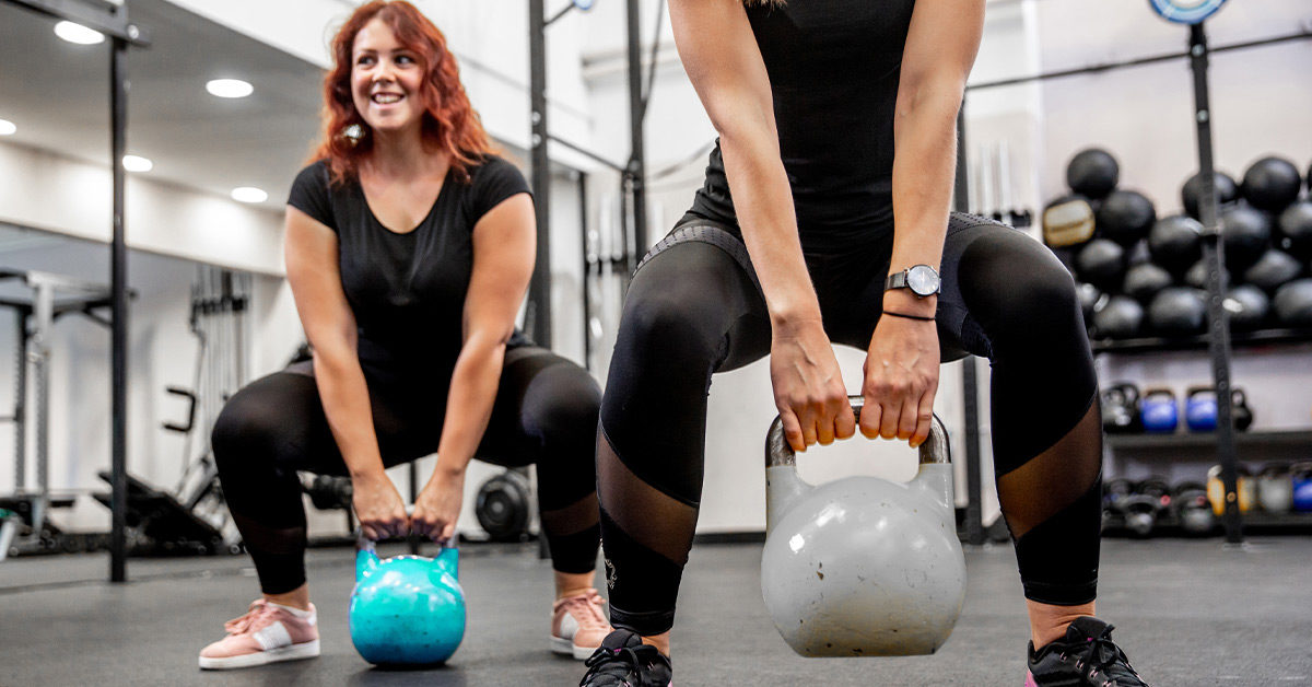 Women in the gym lifting kettlebells