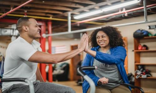Woman in gym giving a high five to a man